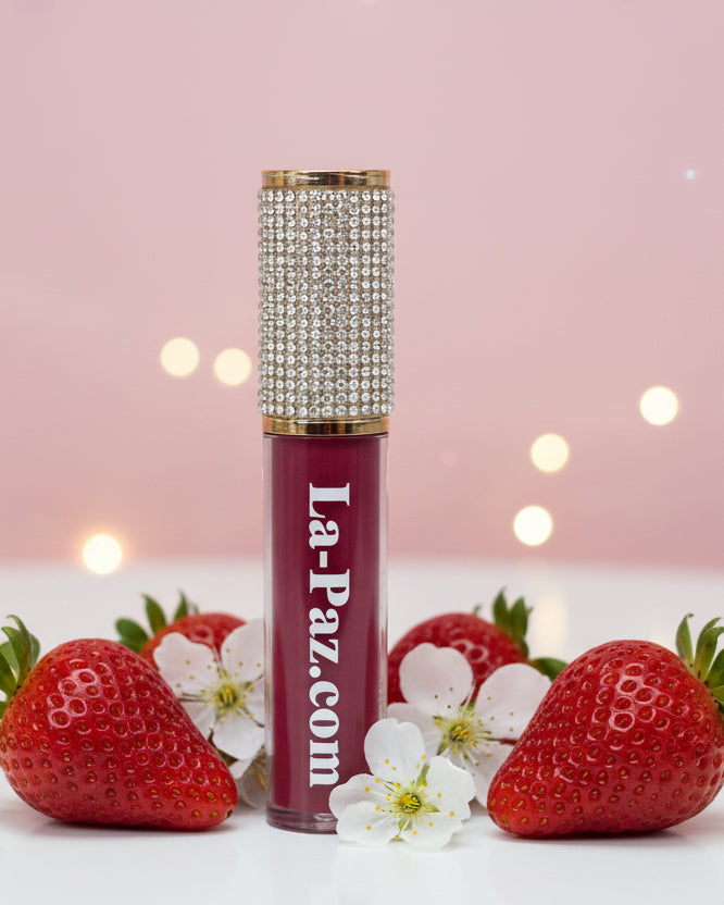 A tube of La-Paz brand lipstick in a strawberry red shade, displayed amidst white flowers.