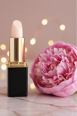 A tube of L'Paige brand lipstick in White Pink Coconut color changing shade, styled with a pink peony and bokeh background.  Presented by La Paz Cosmetics