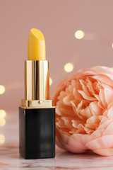 L'Paige Yellow Lemondrop Lipstick that color changes presented by La Paz Cosmetics and styled with a peach peony and bokeh lights in the background