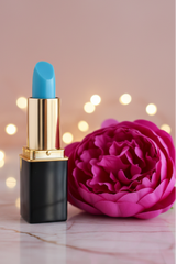 A color changing lipstick by L'Paige in  the color blue orchid which transitions to shades of deep pink to orchid. Presented by La Paz Cosmetics and styled with deep pink peony and a bokeh background
