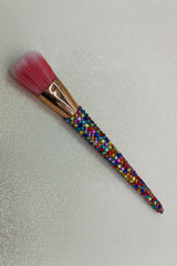 Makeup brush with colorful beaded handle on a glittery background