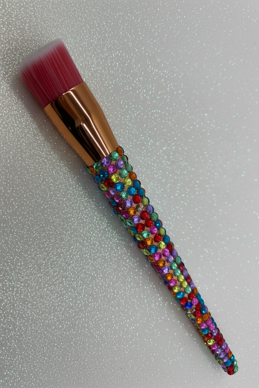 Makeup brush with a colorful crystal handle on a sparkle background