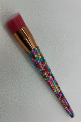 Makeup brush with a colorful crystal handle on a sparkle background