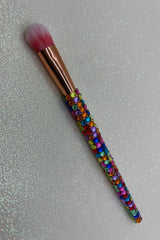 Makeup brush with colorful bead handle on a reflective surface