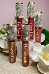 Set of lip glosses with rhinestone caps and colorful labels on a floral background