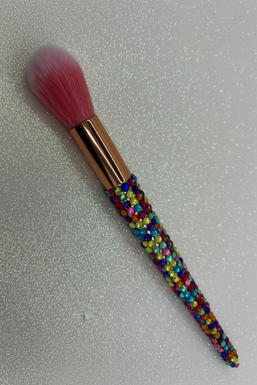 Makeup brush with colorful bead handle on a glittery gray background