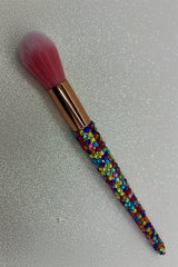 Makeup brush with colorful bead handle on a glittery gray background