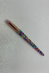 Makeup brush with colorful bead handle on a glittery background