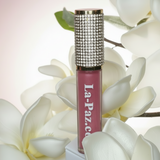 Pink matte lipstick in color diva with rhinestone cap on a white flower background