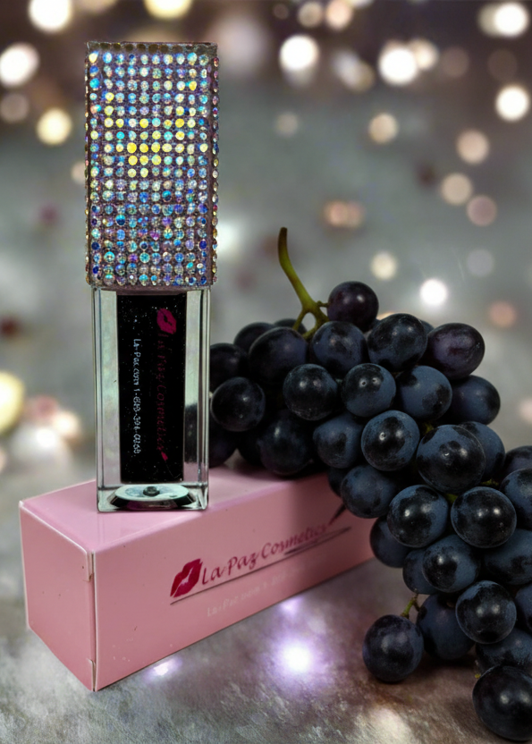 Black Magic color changing lip oil styled with grapes and bokeh lights in background