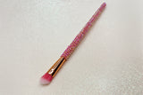 Angled eye makeup brush with pink bristles and a pink rhinestone handle on a sparkly background by La Paz Cosmetics