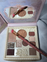 Makeup palette with brushes and decorative packaging on a light background