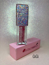 A tube of GiGi Magic moisturizing  lip oil, with  glitter. The product is displayed on a pink box that has the brand name 'La Paz' written on it.