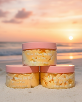 Three jars of 'Miss Moo Belle" body butter in fragrance Brazilian Bum Bum on a beach at sunset