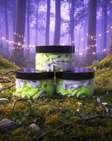 Three jars with cashmere body butter in lavender and green on a forest floor with string lights