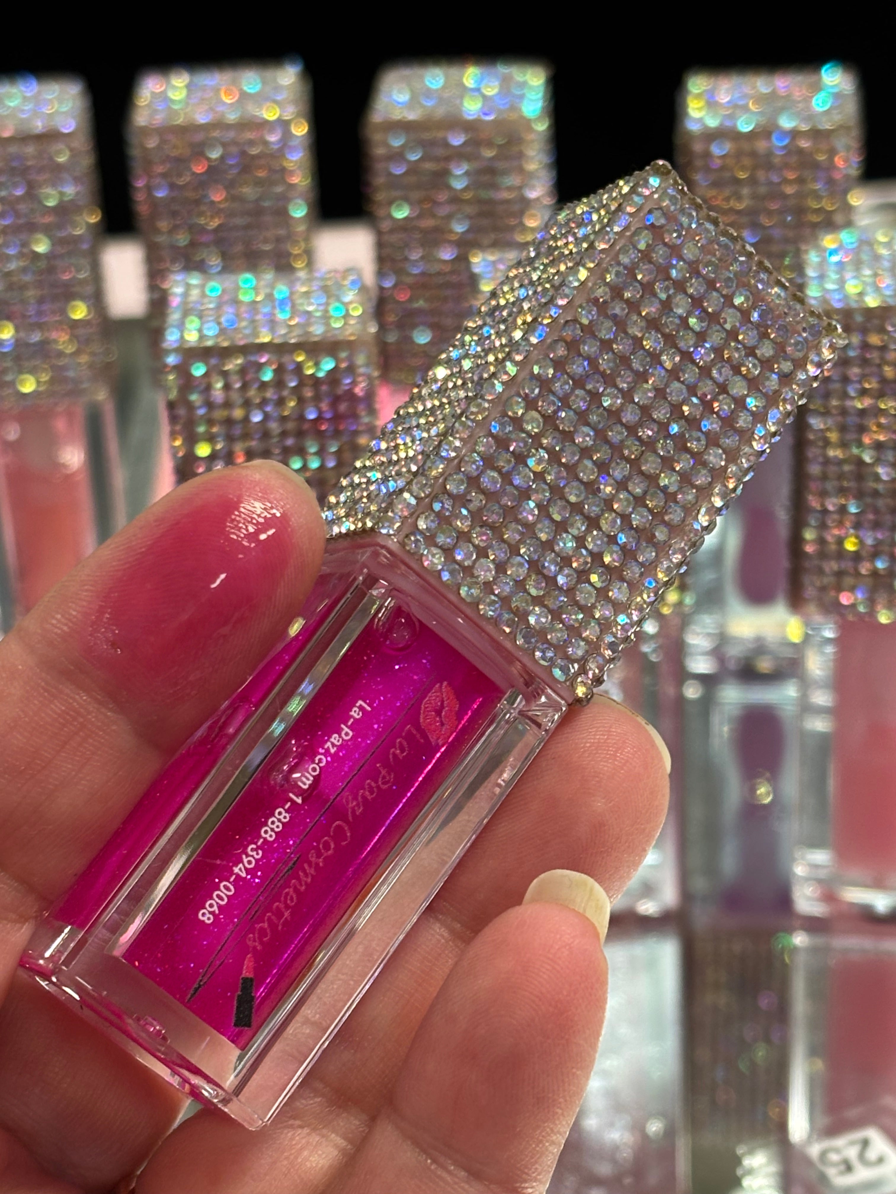 La Paz Cosmetics Jupiter lip oil Held in hand with Jupiter, swatch on one fingertip