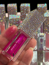 La Paz Cosmetics Jupiter lip oil Held in hand with Jupiter, swatch on one fingertip