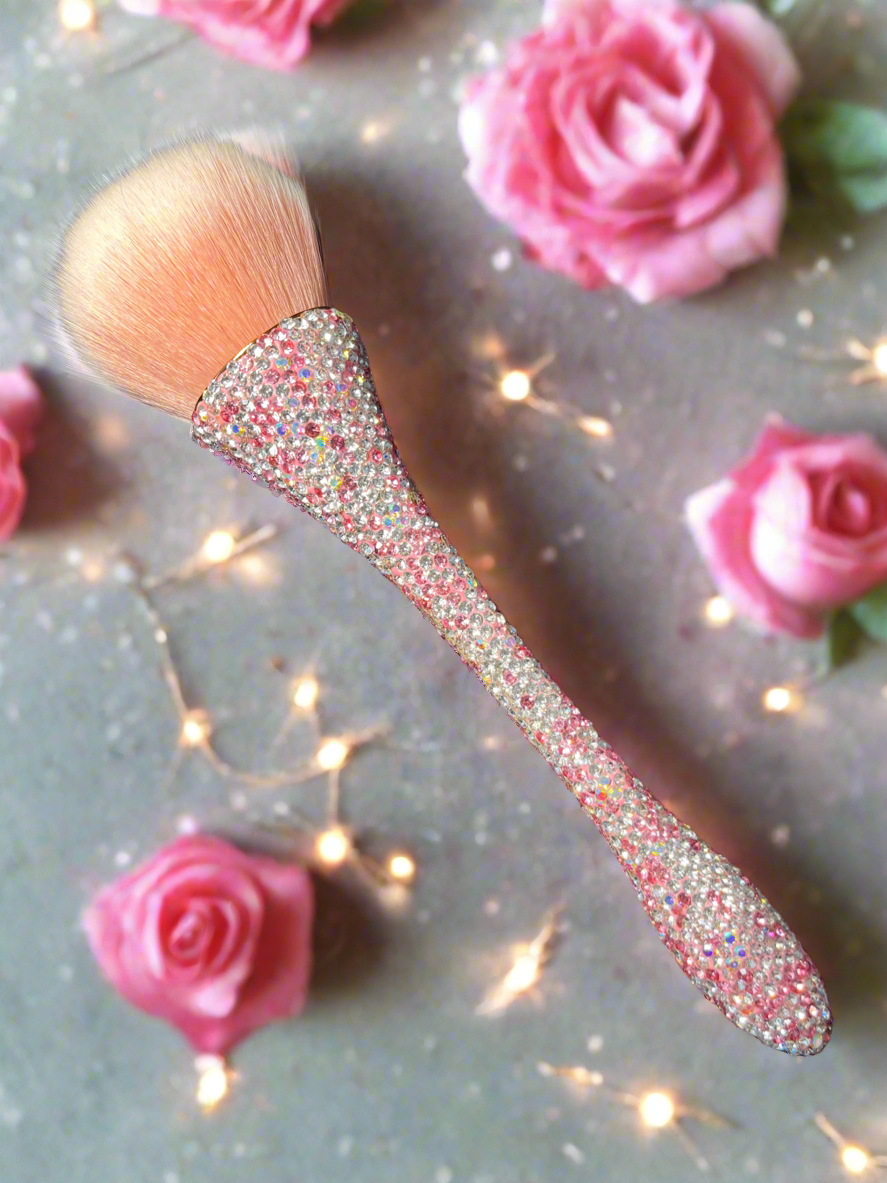 Bling Bling Powder Brush with pink and white rhinestones by La Paz Cosmetics on a decorative background with pink roses and string lights.