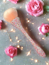 Bling Bling Powder Brush with pink and white rhinestones by La Paz Cosmetics on a decorative background with pink roses and string lights.