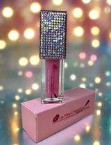 Mercury Lip Oil with rhinestone top on a pink stand against a blurred light background