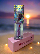 Oceans lip oil with rhinestone top on a pink box against a sunset beach background