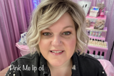 Founder at a cosmetics event with pink decor and wearing Pink Me lip oil.