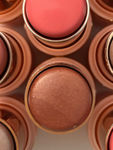 Close-up of La Paz Cosmetics Sun Kissed Glow 8 Shimmer Bronzer Stick showing the warm bronze shimmer formula in a rose gold case, centered among other shades in the collection including blush and highlighter sticks
