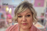Woman with styled hair in a salon setting, with 'Venus' lip oil on her lips