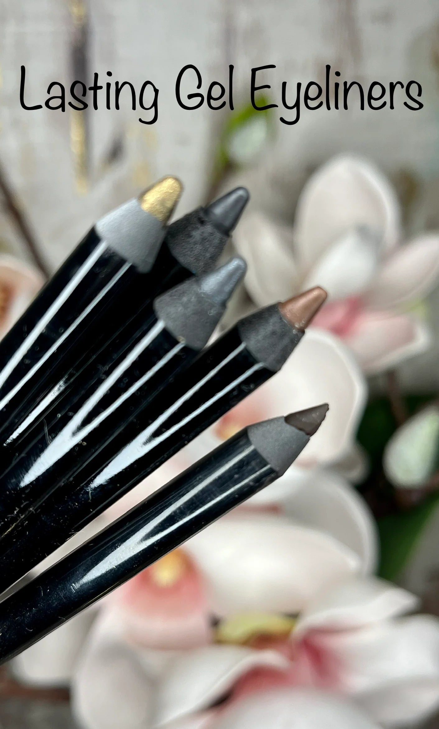 Five La Paz gel eyeliner pencils with black barrels and exposed tips in colors Sienna,  Adorn and Noir arranged diagonally over a blurred background of white and pink flowers. The text 'Lasting Gel Eyeliners' is written at the top.