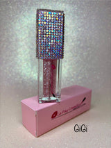 A tube of GiGi Magic moisturizing  lip oil, with  glitter. The product is displayed on a pink box that has the brand name 'La Paz' written on it.