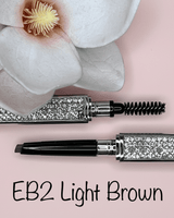 La Paz Cosmetics Luxe Crystal Eyebrow Pencil EB2 Light Brown/Blond open showing dual-ended design with spoolie and precision tip, crystal case on pink background with white orchid