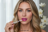 La Paz Cosmetics M07 Pink Poppy Diamond Liquid Matte Lipstick tube with rhinestone cap surrounded by pink poppy flowers on a soft pink background with warm bokeh fairy lights