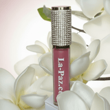 La Paz Cosmetics M19 Diva Diamond Liquid Matte Lipstick tube with rhinestone cap nestled among white magnolia flowers