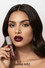 Model holding La Paz M52 Garnet Diamond Liquid Matte Lipstick in deep brownish-red shimmer matte on light grey background