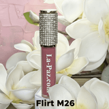 La Paz Cosmetics M26 Flirt Diamond Liquid Matte Lipstick tube with rhinestone cap nestled among white magnolia flowers