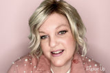 La Paz founder wearing M06 Pucker Up Diamond Liquid Matte Lipstick in warm rosy pink matte in pearl jacket on pink background
