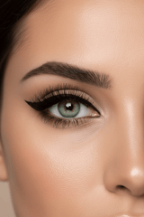 Close-up of a model with green eyes wearing a precise black cat eye wing created with La Paz Cosmetics Luxe Felt Tip Liquid Eyeliner, with defined brows and long lashes on a neutral background