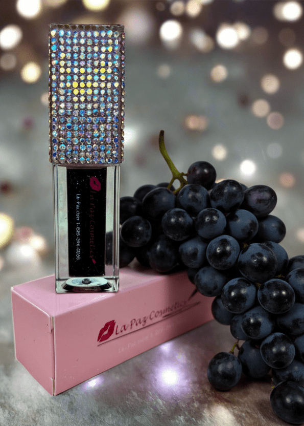 Black Magic color changing lip oil styled with grapes and bokeh lights in background