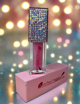 Mercury Lip Oil with rhinestone top on a pink stand against a blurred light background