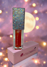 Lip oil in Venus with rhinestone top on a stand against a blurred moonlit sky background