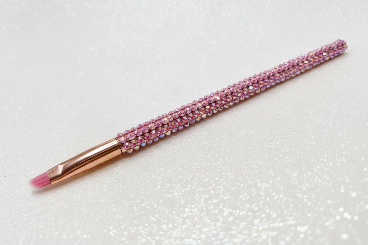 Lip brush with pink bristles and a pink rhinestone handle on a sparkly background by La Paz Cosmetics