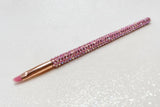 Lip brush with pink bristles and a pink rhinestone handle on a sparkly background by La Paz Cosmetics