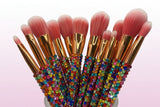 Makeup brushes with gold ferrules and pink bristles, some covered in multicolored crystals