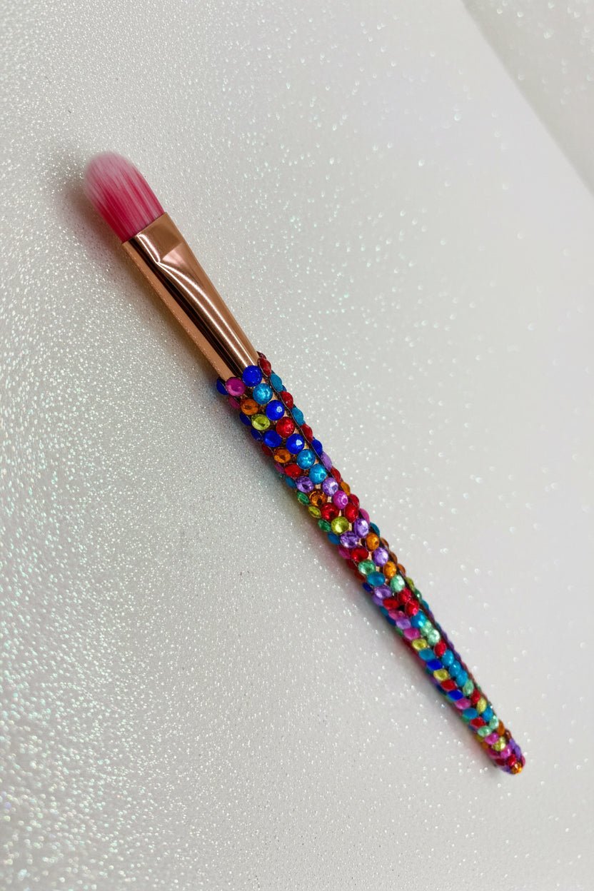 Makeup brush with colorful gemstones on a glittery background
