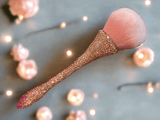 La Paz Cosmetics - Bling Bling Powder brush with pink bristle and rose gold crystal handle against a blurred background