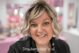 Founder wearing Strawberry clear lip oil and a black top in a blurred background with 'Strawberry clear lip oil' text.
