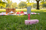 Watermelon Lip Oil in a park with a picnic setup in the background
